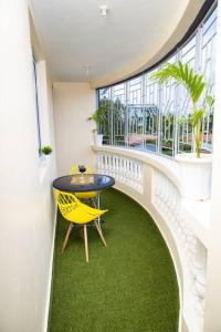 uma varanda com uma mesa e uma cadeira amarela em Royal Haven A3 Spacious 1Br Apartment 10min drive to beach hosts upto 4 guests WiFi - Netflix, 10min drive to beach em Mombaça