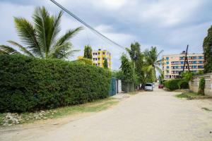 Une rue avec une haie et une voiture conduisant dans une rue dans l'établissement Royal Haven A3 Spacious 1Br Apartment 10min drive to beach hosts upto 4 guests WiFi - Netflix, 10min drive to beach, à Mombasa