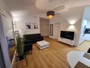 a living room with a black couch and a tv at Panorama Penthouse in Füssen