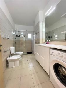 a bathroom with a toilet sink and a washing machine at Duplex Apartment Front Sea in Vlorë