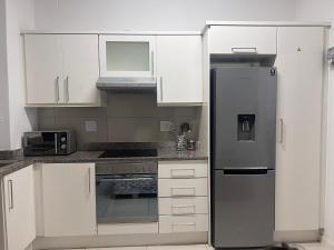 uma cozinha com armários brancos e um frigorífico de aço inoxidável em Umhlanga Ridge One Bedroom Self-Catering apartment em Durban