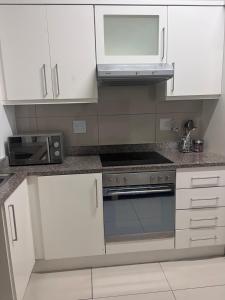 a kitchen with white cabinets and a stove top oven at Umhlanga Ridge One Bedroom Self-Catering apartment in Durban +5 photos