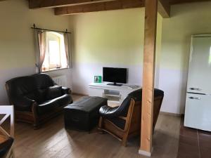 a living room with a black leather couch and a television at Hof am Siel in Butjadingen