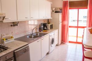 a kitchen with a sink and a washing machine at Amazing and Cosy Apt near the Beach ByCentralgarve in Quarteira