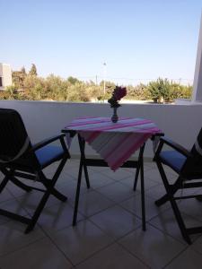 una mesa con 2 sillas y un jarrón de flores en el balcón en Castello Azzurro, en Agia Anna de Naxos