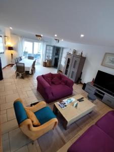 ein Wohnzimmer mit einem lila Sofa und einem Tisch in der Unterkunft Grande maison familiale 300 m de la plage et du centre in Sangatte