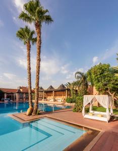 a swimming pool with palm trees and a resort at Berbère Palace in Ouarzazate