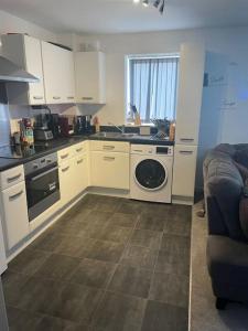 a kitchen with white cabinets and a washer and sink at Lovely 1 Bedroom Condo in Leicester City in Leicester