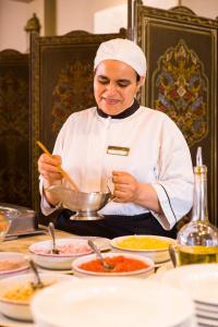 a woman in a chef outfit stirring a bowl of food at Berbère Palace in Ouarzazate