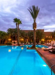 una piscina con palmeras y un hotel en Berbère Palace en Ouarzazate