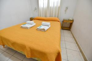 Un dormitorio con una cama amarilla con toallas. en Hotel Simón en Trenque Lauquen
