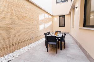 comedor con mesa y sillas junto a una pared de ladrillo en Galmen Apartments en Sevilla