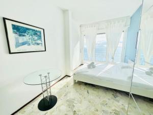 een witte slaapkamer met een bed en een tafel bij Suite Casa del Sole 18 - Fronte Mare in Sanremo