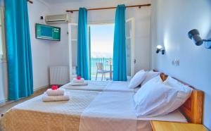 um quarto com uma cama grande com cortinas azuis e uma janela em Nikos Kalamaki Corfu em Apraos
