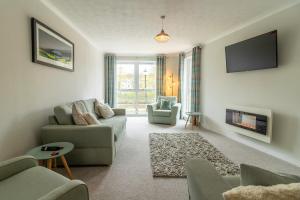 a living room with a couch and chairs and a tv at Fishertown House in Nairn