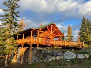 a log cabin in the woods with a large deck at North Haven Campground in Bonners Ferry