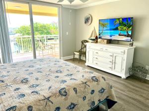 a bedroom with a bed and a flat screen tv at 2x2 Fully Updated Old Town Waterfront Corner Condo in Key West