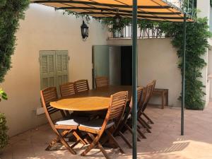una mesa y sillas bajo una sombrilla en un patio en TOULON - Côte d'Azur - Magnifique maison avec piscine privée en Toulon
