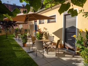 un patio con mesas, sillas y una sombrilla en Pension Ehrenfried - Hotel garni, en Kindberg