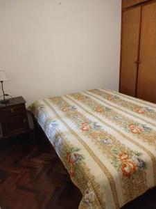 una cama con colcha de flores en una habitación en Capricornio en Salta
