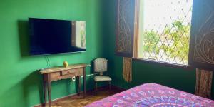 a bedroom with a green wall with a desk and a television at Vila Santê in Belo Horizonte