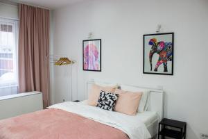 a bedroom with a bed and two pictures on the wall at Town Space Apartment Niš in Niš
