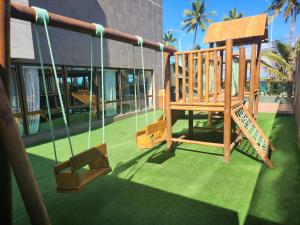 a playground with a swing and a building at Ritz Suites Maceió Flat particular Temporada in Maceió