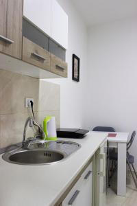 a kitchen sink with a green mug on a counter at Town Space Apartment Niš in Niš