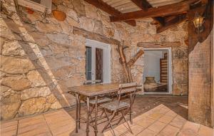 フィガリにあるGorgeous Home In Figari With House A Mountain Viewの石造りの客室(木製のテーブルと椅子付)