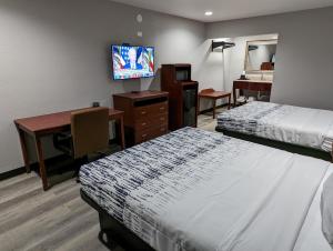 ein Hotelzimmer mit zwei Betten, einem Schreibtisch und einem Fernseher in der Unterkunft OKC Hotel in Oklahoma City