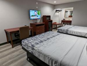 a hotel room with two beds and a desk and a television at OKC Hotel in Oklahoma City