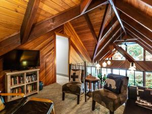 a living room with wooden ceilings and a tv and chairs at Pendleton Pines Lodge in Glacier