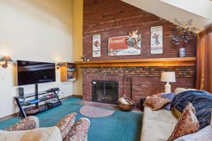 a living room with a brick fireplace and a tv at Sunrise Timberline I4 in Killington