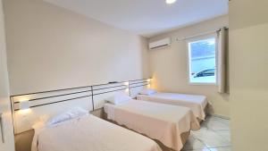 a room with three beds and a window at Residencial Las Rocas I in Florianópolis