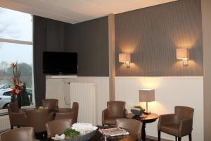 a room with chairs and a table and a tv at Hotel van Dijk in Kampen