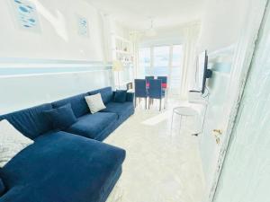 een woonkamer met een blauwe bank en een tafel bij Suite Casa del Sole 16 - Fronte Mare in Sanremo