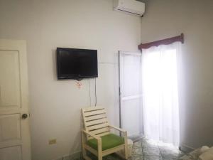 Pokój z krzesłem i telewizorem na ścianie w obiekcie Hostal Tah Itza w mieście Flores