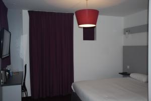 a bedroom with a bed and a red curtain at Kyriad Evreux - Netreville in Évreux