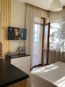 a bedroom with a bed and a tv on the wall at Sunset Yavorov Pomorie in Pomorie