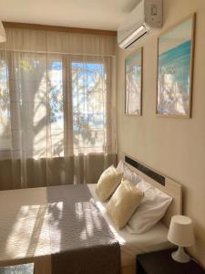 a bedroom with a bed with two pillows and a window at Sunset Yavorov Pomorie in Pomorie