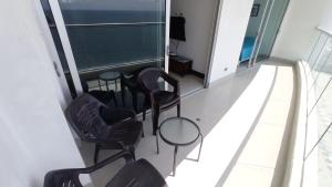 Cette chambre dispose d'un balcon avec des chaises et des tables. dans l'établissement Apartamento frente al mar - Cartagena, à Carthagène des Indes
