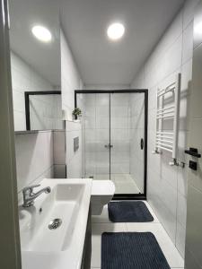 a white bathroom with a sink and a shower at Merkezi konumda yeni dekore edilmiş şık daire in Mersin