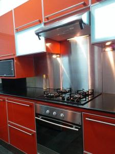 a kitchen with red cabinets and a stove at Beachfront Apartment(roadside- 30 meters to beach) in Flic-en-Flac