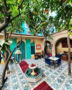 einen Innenhof mit einem Tisch, Stühlen und einem Orangenbaum in der Unterkunft Riad Al Nour in Marrakesch