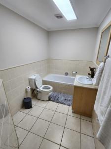 a bathroom with a toilet and a tub and a sink at 13 at Santos in Mossel Bay