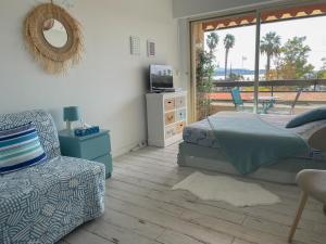 een slaapkamer met een bed, een stoel en een raam bij Les balcons de Bandol Centre ville avec vue mer et face à la plage in Bandol