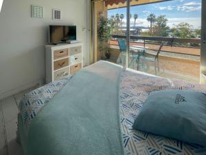 a bedroom with a bed and a television and a balcony at Les balcons de Bandol Centre ville avec vue mer et face à la plage in Bandol