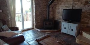 een woonkamer met een tv en een houtkachel bij Charming 2-Bed Cottage within Barn in Merinchal in Mérinchal
