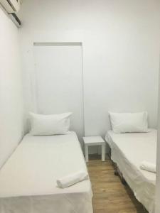 Duas camas num quarto com paredes brancas e uma mesa em Homestay Ibu Shah Alam with pool near icity uitm em Shah Alam