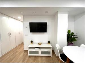 a white living room with a tv and a table at Maximilian Dreams in Madrid